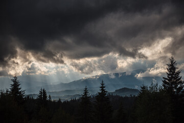 Dark heavy clouds with sunbeams over majestic mountains