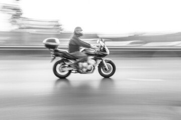 Obraz na płótnie Canvas a man riding a bike. Motorcycle speed motion blur on the road black and white