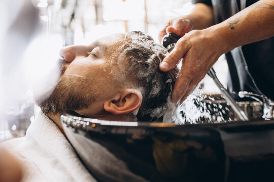 Professional barber, clipper preapring client for haircut at barbershop. Beauty, selfcare, style, fashion and male cosmetics concept.