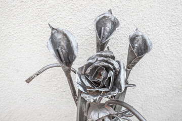 A metal bouquet of roses and calla lilies forged by a blacksmith as a decoration for the house and...