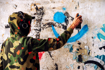 Boy in a hood spraying the wall. Graffiti concept