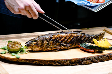 Fried fish on a wood plate at a restaurant