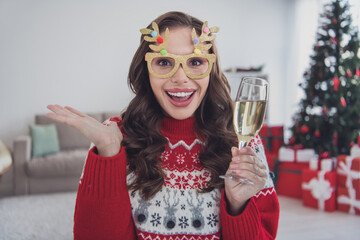 Obraz premium Photo of astonished excited girl celebrate xmas drink champagne wear specs pullover in decorated home indoors