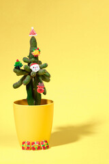 Cactus decorated with small Xmas symbols as alternative Xmas tree on yellow. Vertical orientation.
