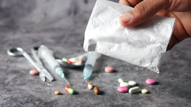 drug addiction concept with hand holding heroine packet on black backgrund 
