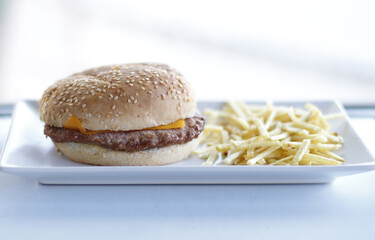 típica hamburguesa de carne con queso cheddar y patatas paja, en su pan de semillas