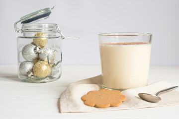 A glass of egg-nog and Christmas decorations on grey background