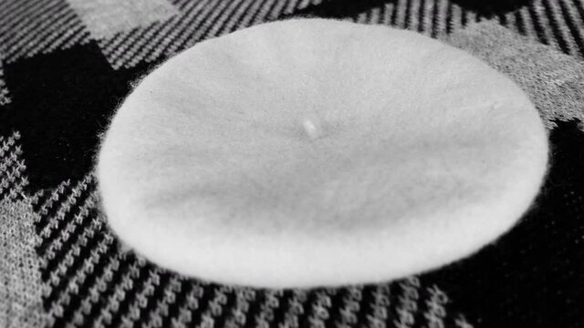 Closeup of a french style beret cap on a handmade knitted grey wool poncho with an irregular geometric modern design. Abstract background pattern.