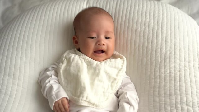 Newborn infant lying on white cushion and getting angry