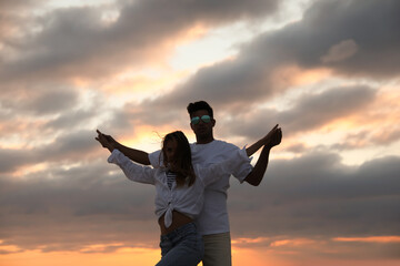 Happy couple dancing outdoors during beautiful sunset
