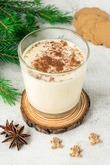 A glass of egg-nog and cookies on grey background