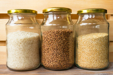 Glass jars of cereals buckwheat rice quinoa for cooking healthy food in glass jars on wooden shelf