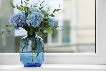 Beautiful blue hortensia flowers in vase on window sill indoors. Space for text