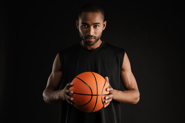 Young sportsman looking at camera while posing with basketball