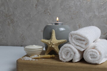 Fototapeta na wymiar salt for bath massage peeling spa relax massage. Home salon body care. Beauty. White towels starfish salt candles on a wooden tray on a gray background side view