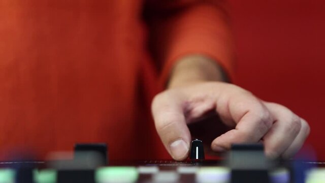 Hand of dj playing music with sound mixer device filmed in close up video clip. Djs hand cutting tracks with crossfader regulator on audio mixer 