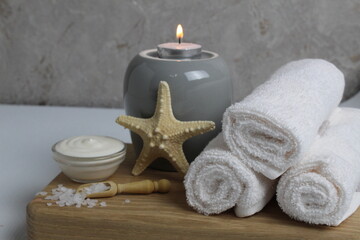 Obraz na płótnie Canvas salt for bath massage peeling spa relax massage. Home salon body care. Beauty. White towels starfish salt candles on a wooden tray on a gray background side view