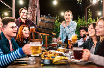 Happy men and women having fun drinking out at beer garden - Social gathering life style concept on...