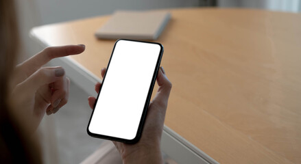 Mockup image blank white screen cell phone.women hand holding texting using mobile on desk at home office.