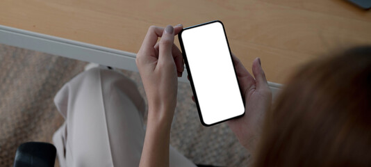 Mockup image blank white screen cell phone.women hand holding texting using mobile on desk at home...