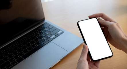 Mockup image blank white screen cell phone.women hand holding texting using mobile on desk at home office.