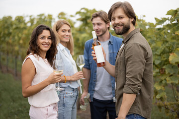 Joyful european friends tasting local wine near vineyards in countryside. Concept of winemaking. Young men and women enjoying time together. Idea of friendship and leisure. Green tourism