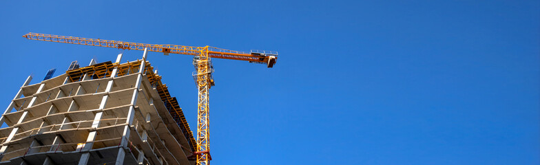Construction crane on a highrise building construction site, blue sky background, banner with copy space photo