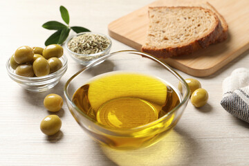 Glass bowl with fresh olive oil on white wooden table