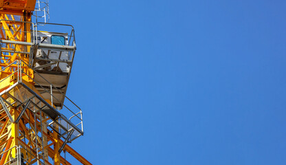 Closeup view of the control cabin of a construction tower crane. Construction crane against blue sky with copy space