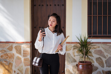 Serious ethnic woman with envelope checking smartphone