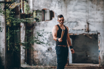 Strong Muscular Brutal Man in Black Tank Top with Baseball Bat Walks in Empty Grunge Hall