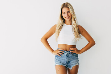 young blonde girl in short denim shorts and a white t-shirt on white background