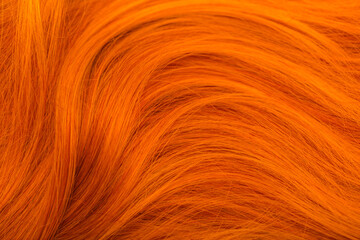 Red hair. Background hair closeup. Female long red-haired close-up as a background. Beautifully laid carroty wavy shiny curls. Hair coloring.Hairdressing procedures. Copy space with space for text.
