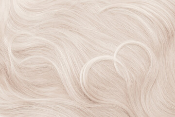 Fototapeta premium Background hair closeup. Female long blond hair close-up as a background. Beautifully laid wavy shiny curls. Hair coloring. Hairdressing procedures. Copy space with space for text.