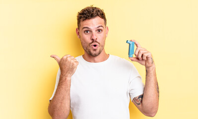 young handsome man looking astonished in disbelief. asthma concept