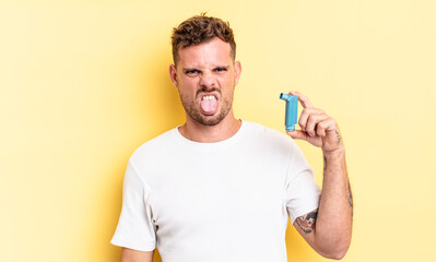 young handsome man feeling disgusted and irritated and tongue out. asthma concept