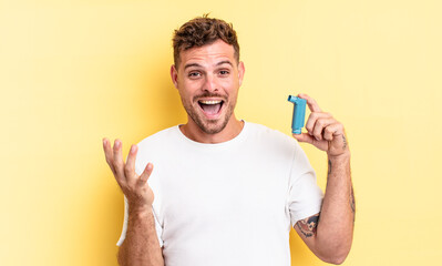 young handsome man feeling extremely shocked and surprised. asthma concept