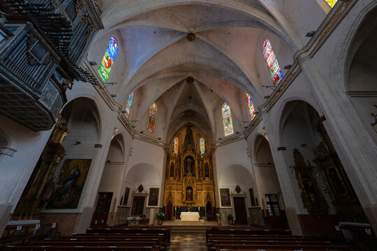 The interior of the old historic church of Felanitx on the Spanish Mediterranean island of Mallorca. To the right and left are benches and an altar at the back. At the top right is the organ.