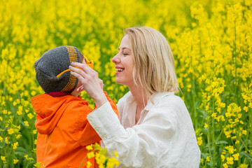 Blonde mother with a son on rapeseed field