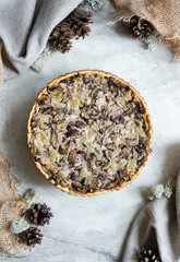 Mushroom pie top view winter mood. Quiche with champignons and onions. Unsweetened tart on a light background.