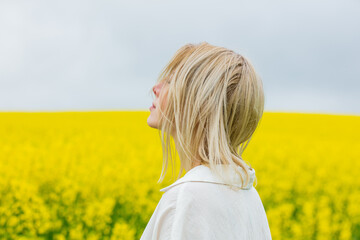 Beautiful blonde in white shirt on yellow rapeseed field