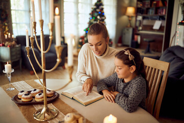 Jewish mother and daughter read Tanakh during Hanukkah at home.