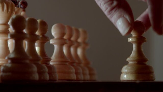 The hand takes a pawn and starts a chess game with the first move.