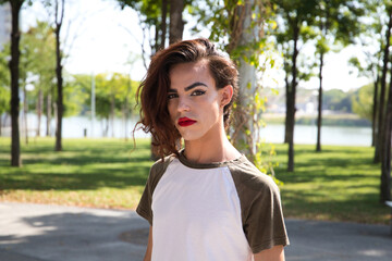 young latina transsexual woman is in a park where she is going to start doing her make-up for her big change from boy to girl. Concept of diversity, transgender, and freedom of homosexual expression. - obrazy, fototapety, plakaty