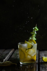 Cocktail with lemon, lime and ice in a glass on a dark background
