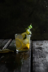Cocktail with lemon, lime and ice in a glass on a dark background