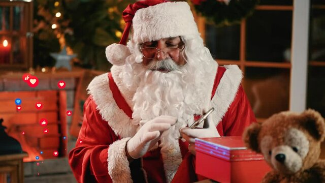 Santa streaming live broadcast video on screen  with a lot of emoji like and emotion love. Happy Santa Claus talking to camera sitting at home 