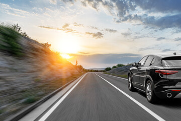 Grijze auto op een schilderachtige weg. Auto op de weg omringd door een prachtig natuurlijk landschap in de stralen van zonsondergang of zonsopgang.