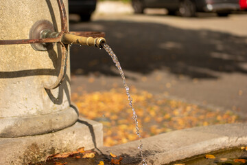 Old stone and sculpted metal public drinking water fountain. European city, summer day, close up shot, no people