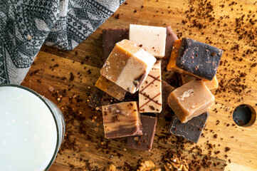 Mixed fudge sweets on rustic and vintage wooden chopping board with glass of milk